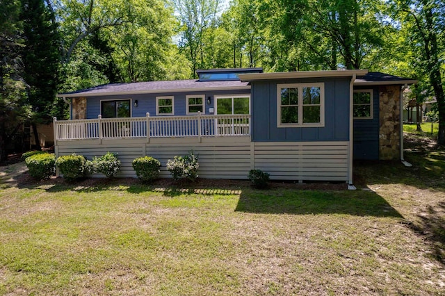view of front of property featuring a front lawn, a deck, and board and batten siding
