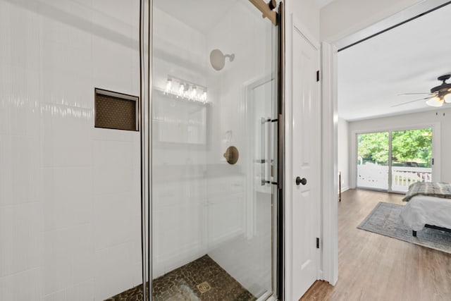 ensuite bathroom featuring a shower stall, a ceiling fan, and wood finished floors