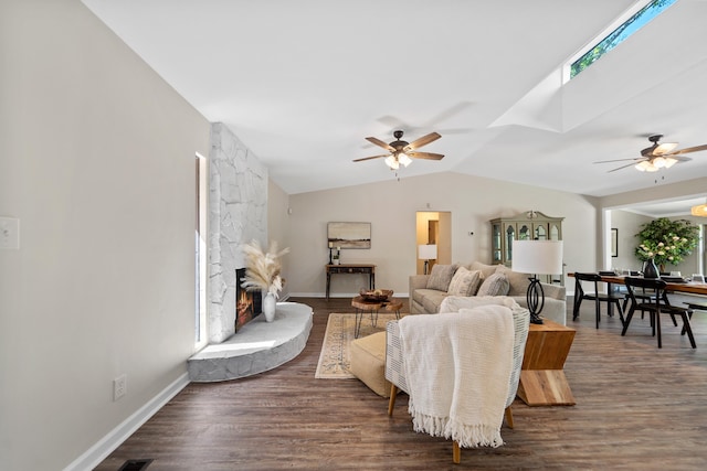living room with vaulted ceiling with skylight, a ceiling fan, and dark wood-style flooring
