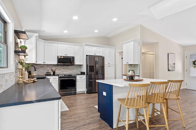 kitchen featuring dark wood finished floors, lofted ceiling, appliances with stainless steel finishes, and a sink