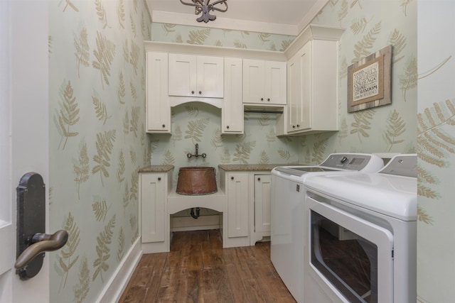 clothes washing area with cabinets, washing machine and clothes dryer, and dark hardwood / wood-style floors