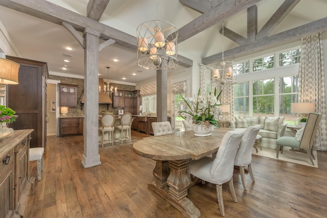 dining area with decorative columns, dark wood-type flooring, an inviting chandelier, and beamed ceiling