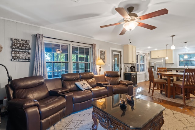 living room featuring light wood-type flooring, ceiling fan, and ornamental molding