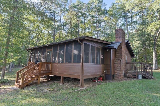 exterior space with a yard, a chimney, and a sunroom