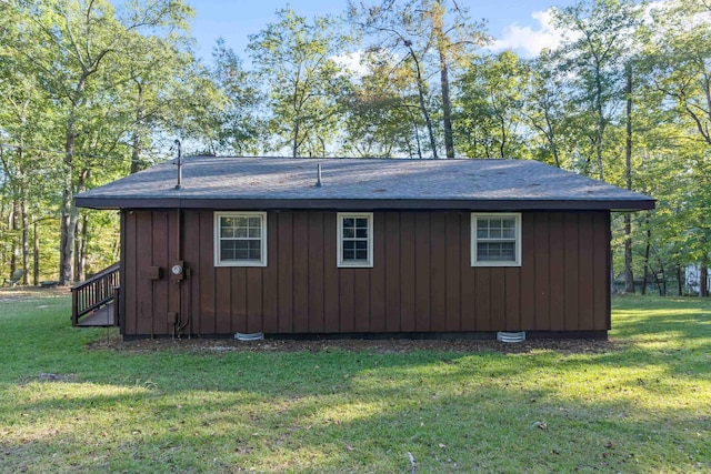 view of home's exterior with a yard, board and batten siding, and roof with shingles