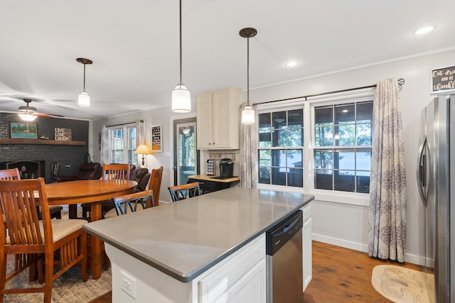 kitchen with dark wood-type flooring, decorative light fixtures, appliances with stainless steel finishes, a fireplace, and ceiling fan