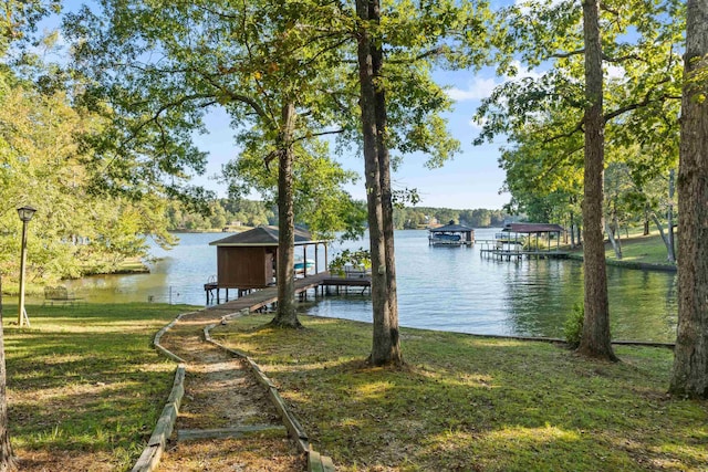 view of dock featuring a water view, boat lift, and a lawn