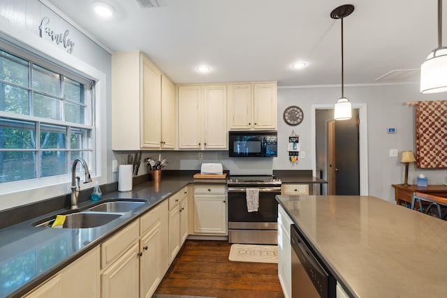 kitchen with dark wood-style flooring, appliances with stainless steel finishes, cream cabinets, and a sink