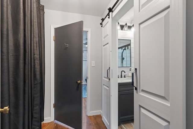 hall with a barn door, dark wood-style floors, and a sink