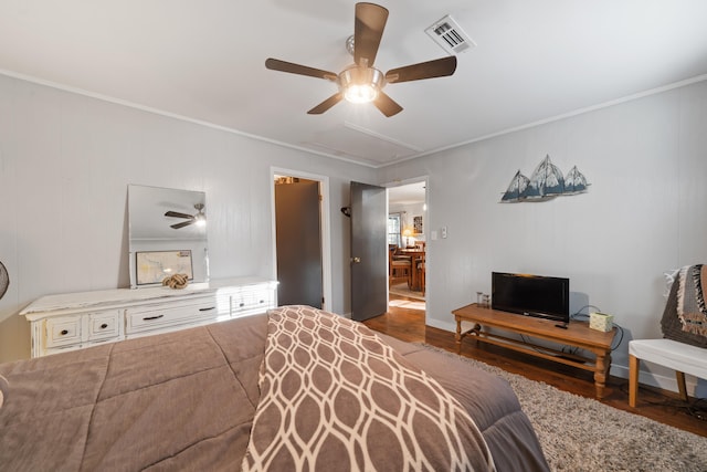 bedroom with wood finished floors, visible vents, attic access, ceiling fan, and ornamental molding