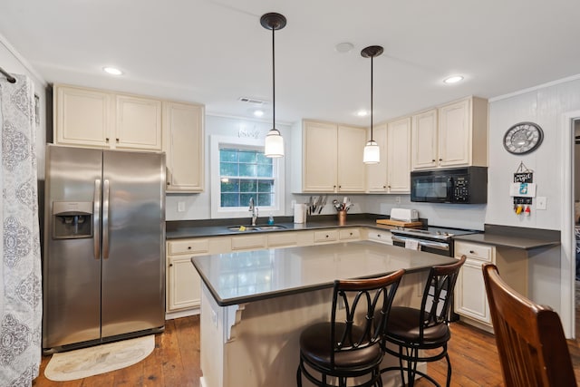 kitchen featuring dark countertops, dark wood finished floors, appliances with stainless steel finishes, and a sink