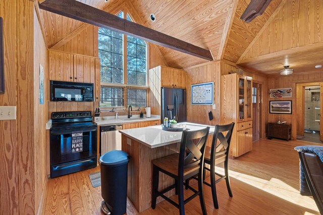 125 Secoffee Dr, Eatonton, GA 31024 - kitchen with beamed ceiling, wooden walls, black appliances, and light wood finished floors
