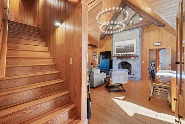 125 Secoffee Dr, Eatonton, GA 31024 - stairway with lofted ceiling with beams, wood finished floors, a stone fireplace, wood walls, and a notable chandelier