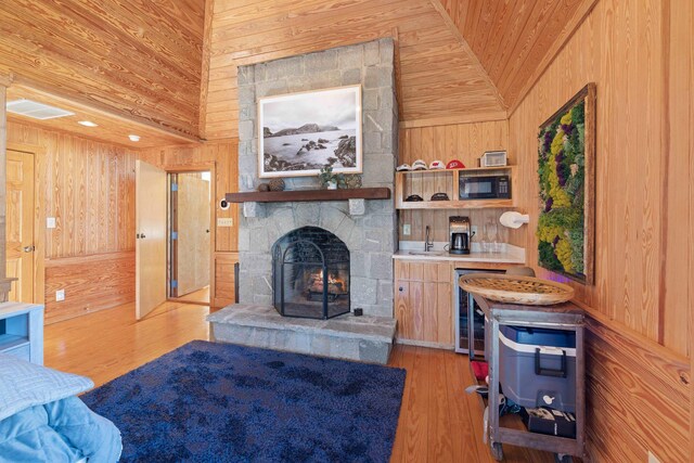125 Secoffee Dr, Eatonton, GA 31024 - living area with wine cooler, vaulted ceiling, wood walls, a stone fireplace, and wood finished floors