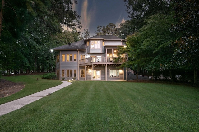 back house at dusk with a wooden deck and a lawn