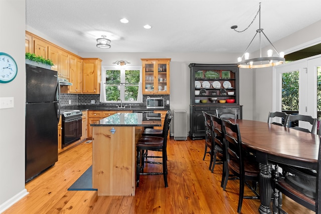 kitchen with sink, stove, a center island, tasteful backsplash, and black fridge