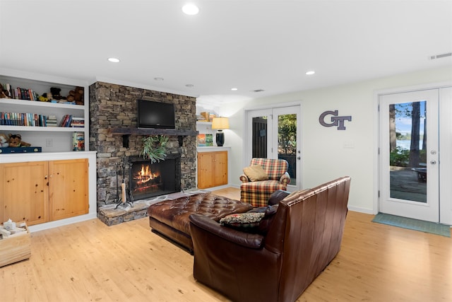 living room featuring french doors, a healthy amount of sunlight, a fireplace, and light hardwood / wood-style flooring