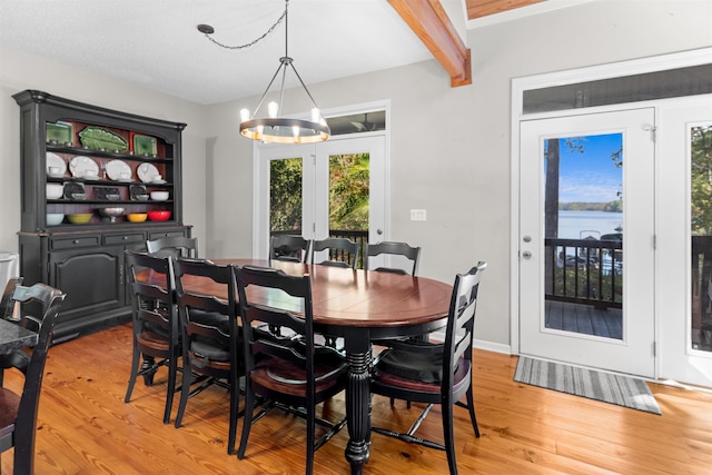 dining area with beam ceiling, a chandelier, and light hardwood / wood-style floors