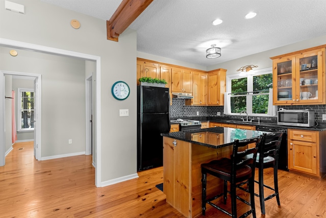 kitchen featuring sink, black appliances, a center island, a wealth of natural light, and backsplash