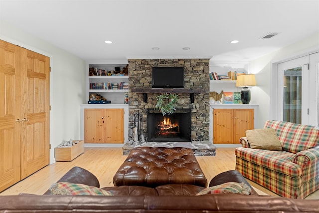 living room featuring a fireplace, built in features, and light wood-type flooring