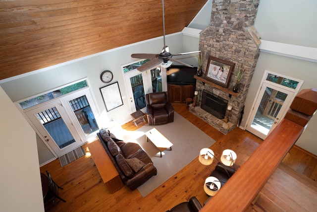 living room with plenty of natural light, wood-type flooring, a stone fireplace, and wooden ceiling