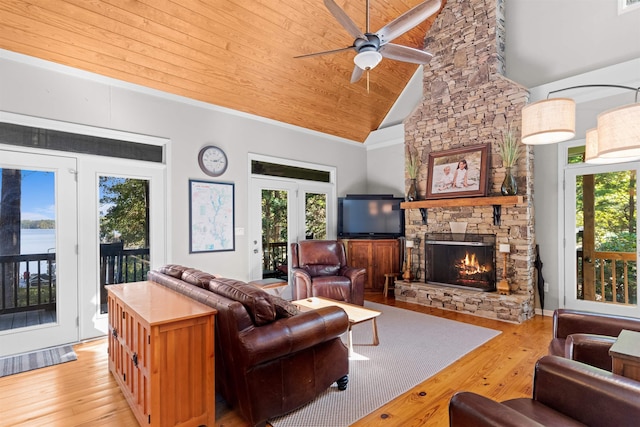 living room with a stone fireplace, a wealth of natural light, and light wood-type flooring