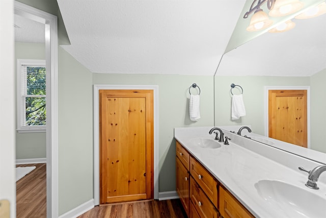 bathroom with vanity, hardwood / wood-style flooring, vaulted ceiling, and a textured ceiling