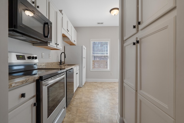 kitchen with visible vents, a sink, light stone counters, appliances with stainless steel finishes, and baseboards