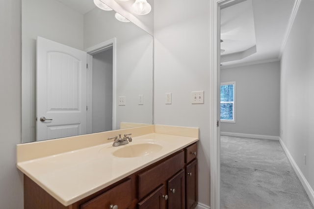 bathroom featuring baseboards, a raised ceiling, vanity, and crown molding