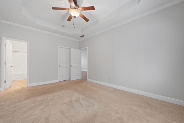 unfurnished bedroom with a tray ceiling, crown molding, baseboards, and light carpet