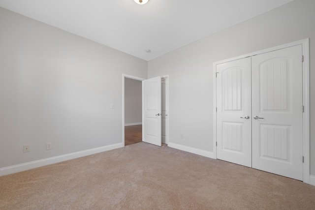 unfurnished bedroom with carpet, a closet, and baseboards