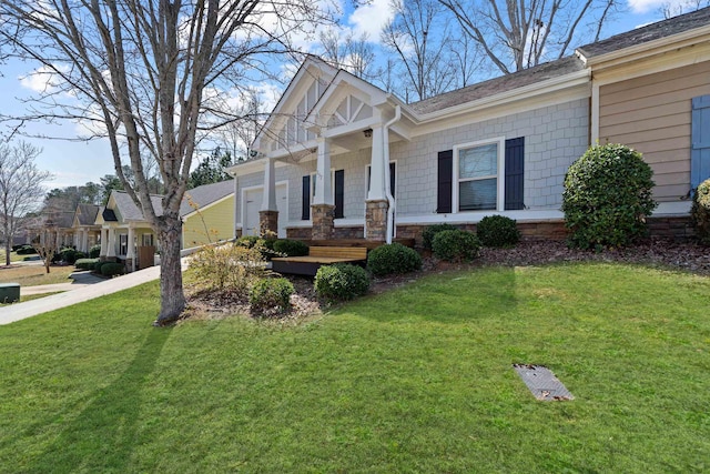 craftsman-style home with a front yard, an attached garage, covered porch, and driveway