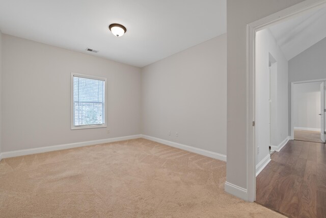 spare room with carpet, lofted ceiling, baseboards, and visible vents