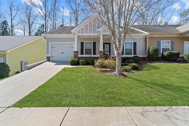 craftsman-style house featuring stone siding, a front yard, concrete driveway, and an attached garage