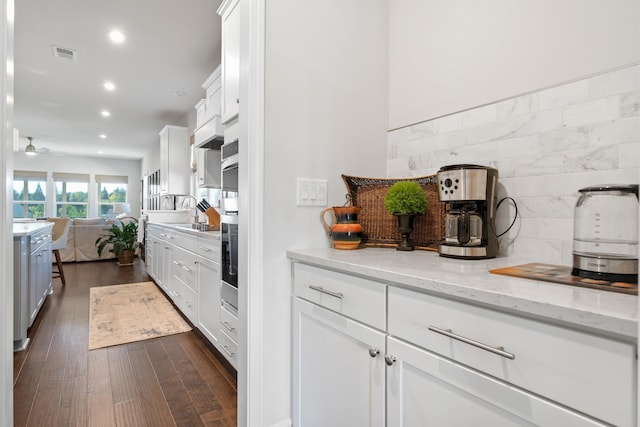 kitchen featuring dark wood-type flooring, light stone countertops, and white cabinets