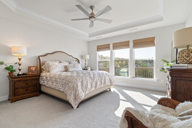 bedroom featuring light carpet, ceiling fan, and a tray ceiling