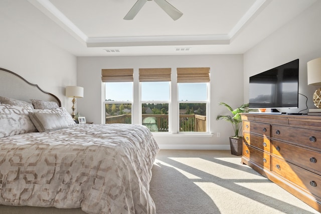 bedroom with ceiling fan, light colored carpet, and a tray ceiling