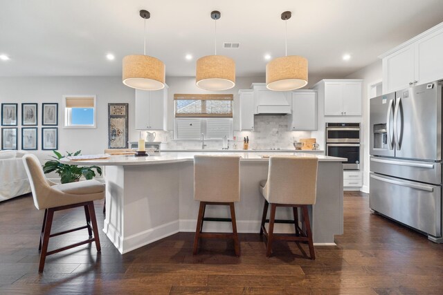 kitchen with a breakfast bar, pendant lighting, white cabinets, a center island, and stainless steel appliances