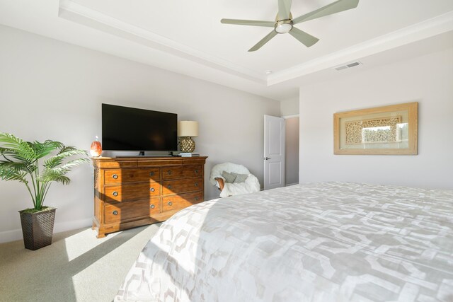 bedroom with ceiling fan, carpet flooring, and a tray ceiling