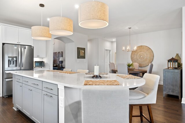 kitchen with white cabinetry, hanging light fixtures, dark hardwood / wood-style floors, a kitchen island, and stainless steel fridge with ice dispenser