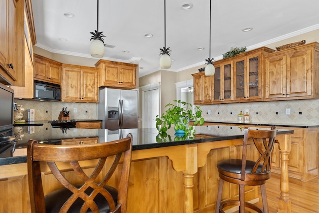 kitchen with decorative light fixtures, stainless steel fridge, ornamental molding, and a kitchen bar