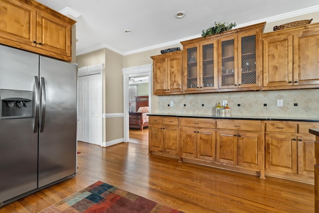 kitchen featuring hardwood / wood-style flooring, ornamental molding, stainless steel fridge, and decorative backsplash