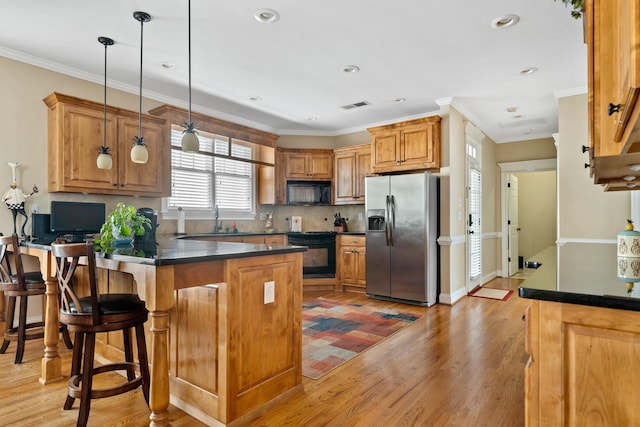 kitchen featuring ornamental molding, pendant lighting, light hardwood / wood-style floors, and black appliances