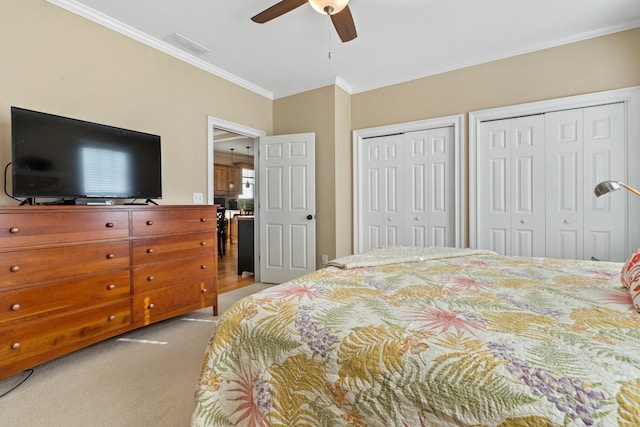 bedroom with crown molding, ceiling fan, light carpet, and two closets