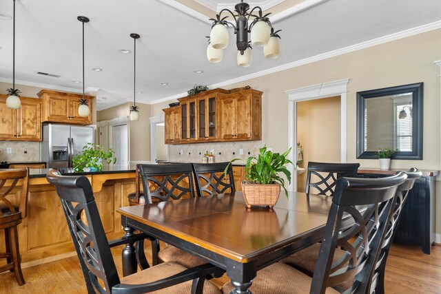 dining space featuring a notable chandelier, crown molding, and light wood-type flooring