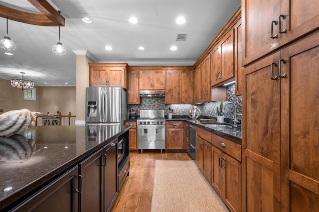 kitchen with dark stone countertops, sink, decorative light fixtures, and stainless steel appliances