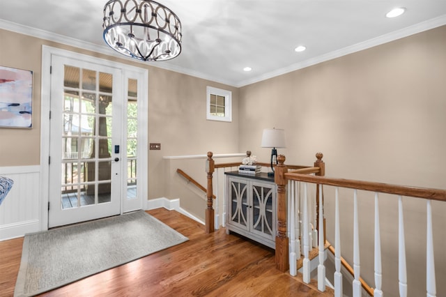 entryway with hardwood / wood-style floors, crown molding, and a notable chandelier