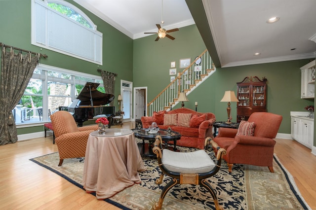 1811 Snug Harbor Dr, Greensboro, GA 30642 - living room featuring ornamental molding, light wood-style floors, stairs, a ceiling fan, and a towering ceiling
