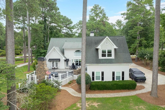 1811 Snug Harbor Dr, Greensboro, GA 30642 - view of front facade featuring stucco siding, roof with shingles, a chimney, view of scattered trees, and a deck
