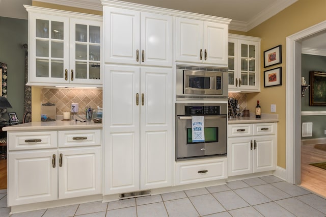 1811 Snug Harbor Dr, Greensboro, GA 30642 - kitchen featuring appliances with stainless steel finishes, ornamental molding, decorative backsplash, light countertops, and light tile patterned flooring